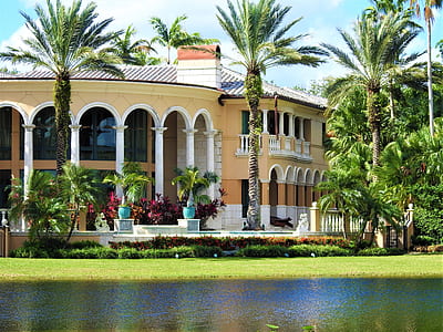 photography of yellow and white concrete building surrounded by palm trees at daytime thumbnail