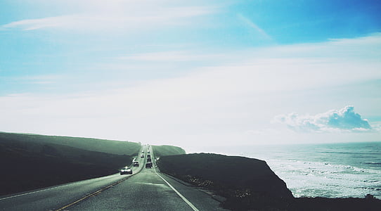 vehicles passing by road by the sea thumbnail