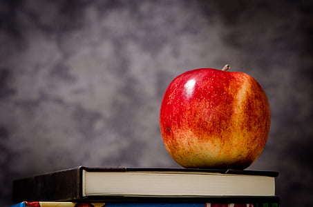red apple on top on black covered book thumbnail