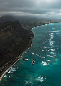 rock cliff near body of water under cloudy skies thumbnail
