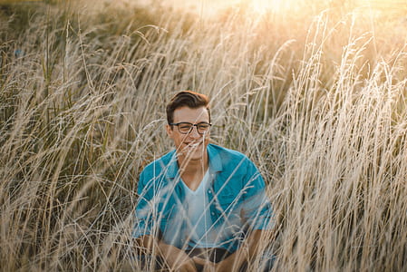 man seating on ground surrounded by grass thumbnail
