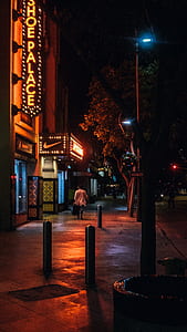man walking on sidewalk during night time thumbnail