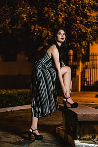 Woman Reaching On Sandal On Bench At Night thumbnail