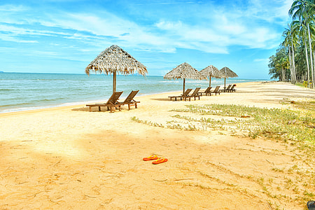 four beach huts in brown sandy beach at daytime thumbnail