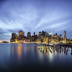 cityscape by water during golden hour with lights turned on thumbnail