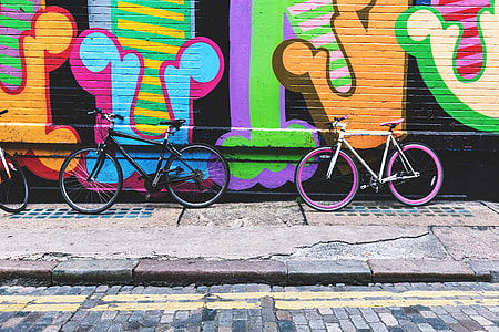 Bicycles stand against a street-art covered wall in the city thumbnail