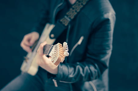 man playing guitar wearing black leather jacket thumbnail