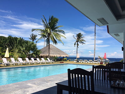 lounge chairs in front of in-ground pool under sunny sky thumbnail