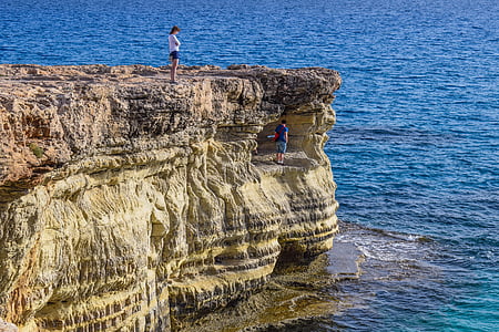 woman standing on rock near body of water thumbnail