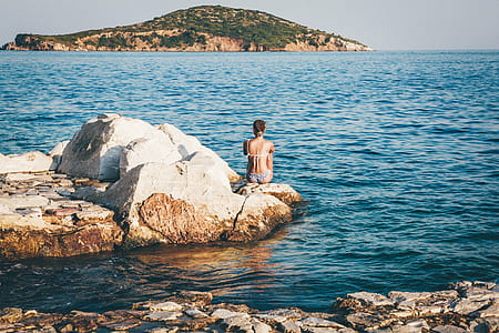woman wearing bikini sitting on the rock thumbnail