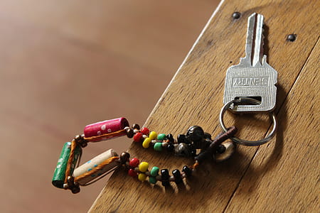 gray Sentry key with multicolored keychain on brown wooden surface thumbnail