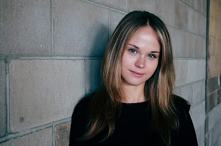 woman wearing black top standing near gray concrete wall thumbnail