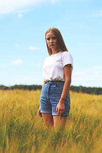 Woman Wearing White Crew-neck T-shirt, Blue Denim Cuff Short Shorts While Standing on Grass Field thumbnail