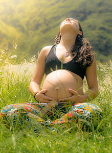 pregnant woman sitting on grassy field holding tummy thumbnail