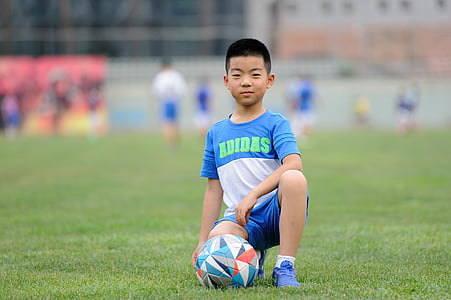 boy kneeling on ground beside soccer ball thumbnail
