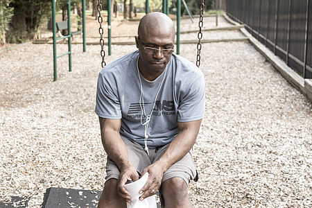 man wearing grey shirt sits on swing at park during daytime thumbnail