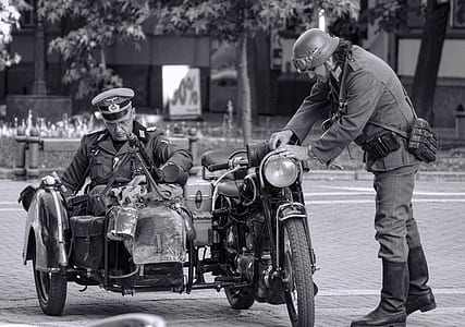 grayscale photo of man on motorcycle with side car near man standing thumbnail
