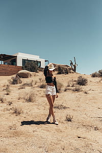 standing woman holding cowboy hat near white building at daytime thumbnail