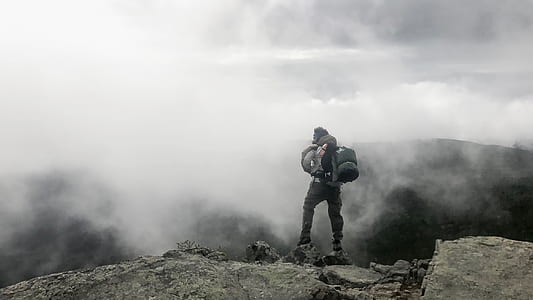 person standing on mountain peak in front of fogs thumbnail