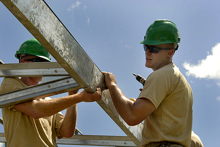 man wearing beige shirt and green safety helmet holding white steel bars thumbnail