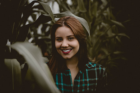 woman standing beside corn plant while smiling thumbnail