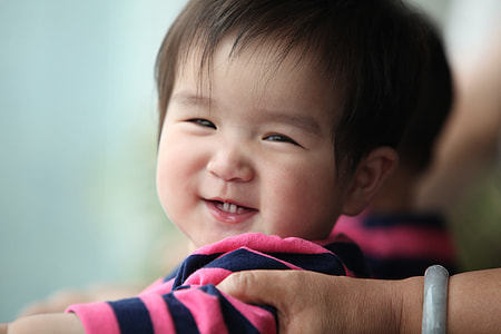 macro shot of smiling baby boy wearing black and blue stripe shirt thumbnail
