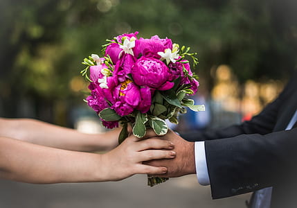 woman and man holding bunch of purple petaled flowers thumbnail