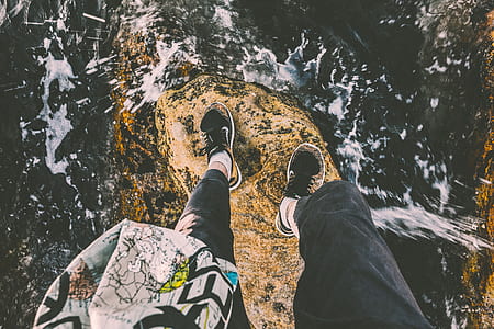 person standing on cliff near body of water thumbnail