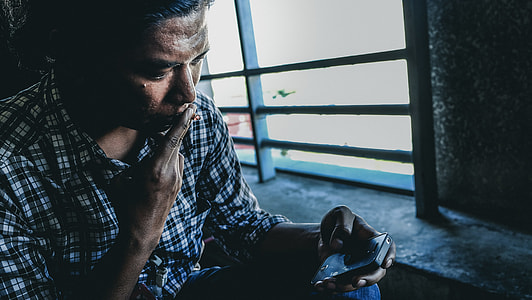 person in black and white plaid dress shirt holding iPhone near window thumbnail