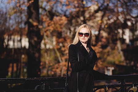 woman in black coat standing in front of black fence thumbnail