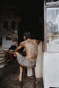 topless man sitting on stool near glass counter thumbnail