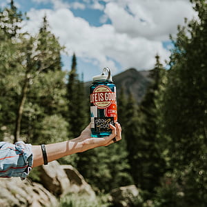 person holding a blue tumbler near forest macro shot thumbnail
