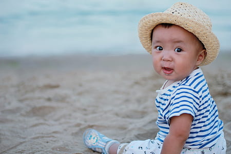 selective focus photography of baby sitting on beach thumbnail