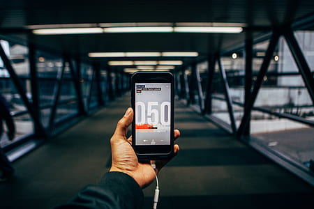 person holding black smartphone while walking on footbridge thumbnail