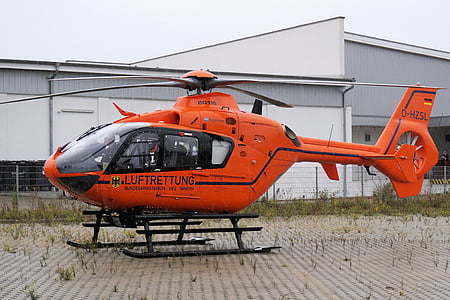 orange helicopter on ground near building thumbnail