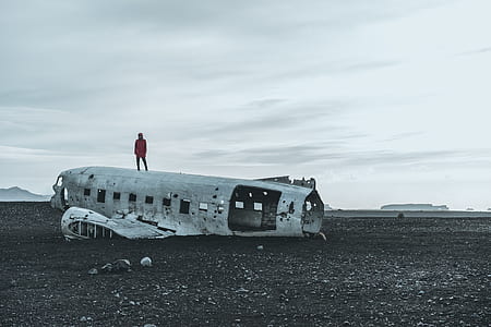 person standing on crashed plane at gray open field during daytime thumbnail