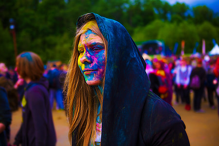 woman with face paint wearing hoodie in crowd of people thumbnail