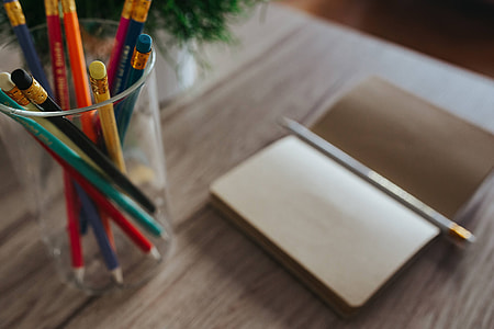 Notebooks with colourful pencils on a wooden desk thumbnail