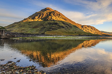 green and brown mountain beside body of water during daytime thumbnail