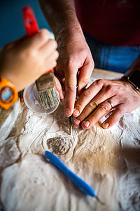 person carving wood beside person holding brush thumbnail