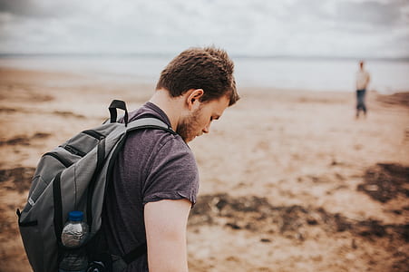 selective focus photography of man wearing gray backpack at beach thumbnail