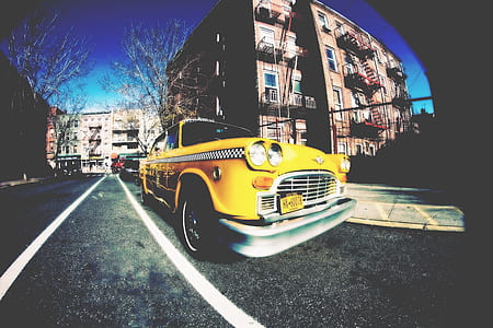 fisheye photography of classic yellow taxi parked on sidewalk near building thumbnail