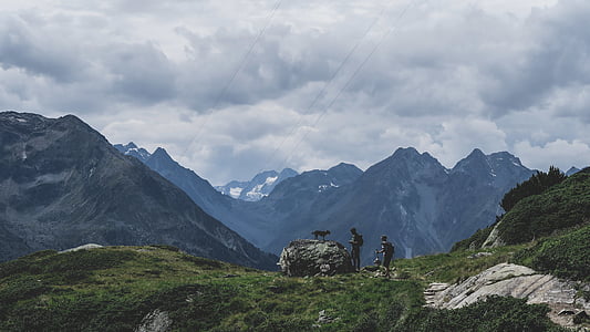 photography of two person standing on green grass front of mountain at daytime thumbnail