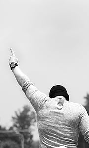 man wearing knit hat pointing his left hand at the sky during day thumbnail
