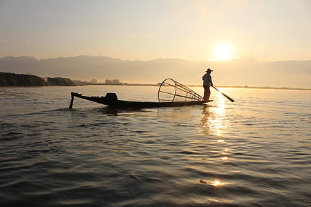 fisherman at middle of water during sunset thumbnail