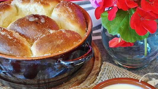 baked bread on black round container beside red petaled flowers thumbnail