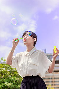 Photo of Woman in White Blouse Playing With Bubbles thumbnail