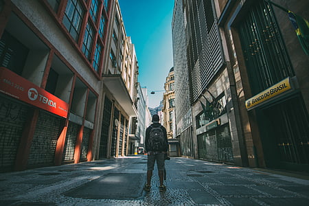 man standing in the middle of street surrounded with buildings thumbnail