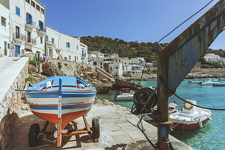 blue, orange, and white boat beside body of water thumbnail