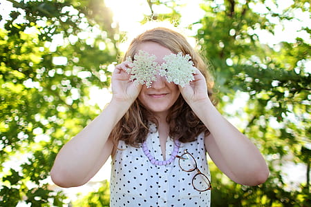 Woman Wearing White and Black Dotted Sleeveless Top Holding White Flower thumbnail